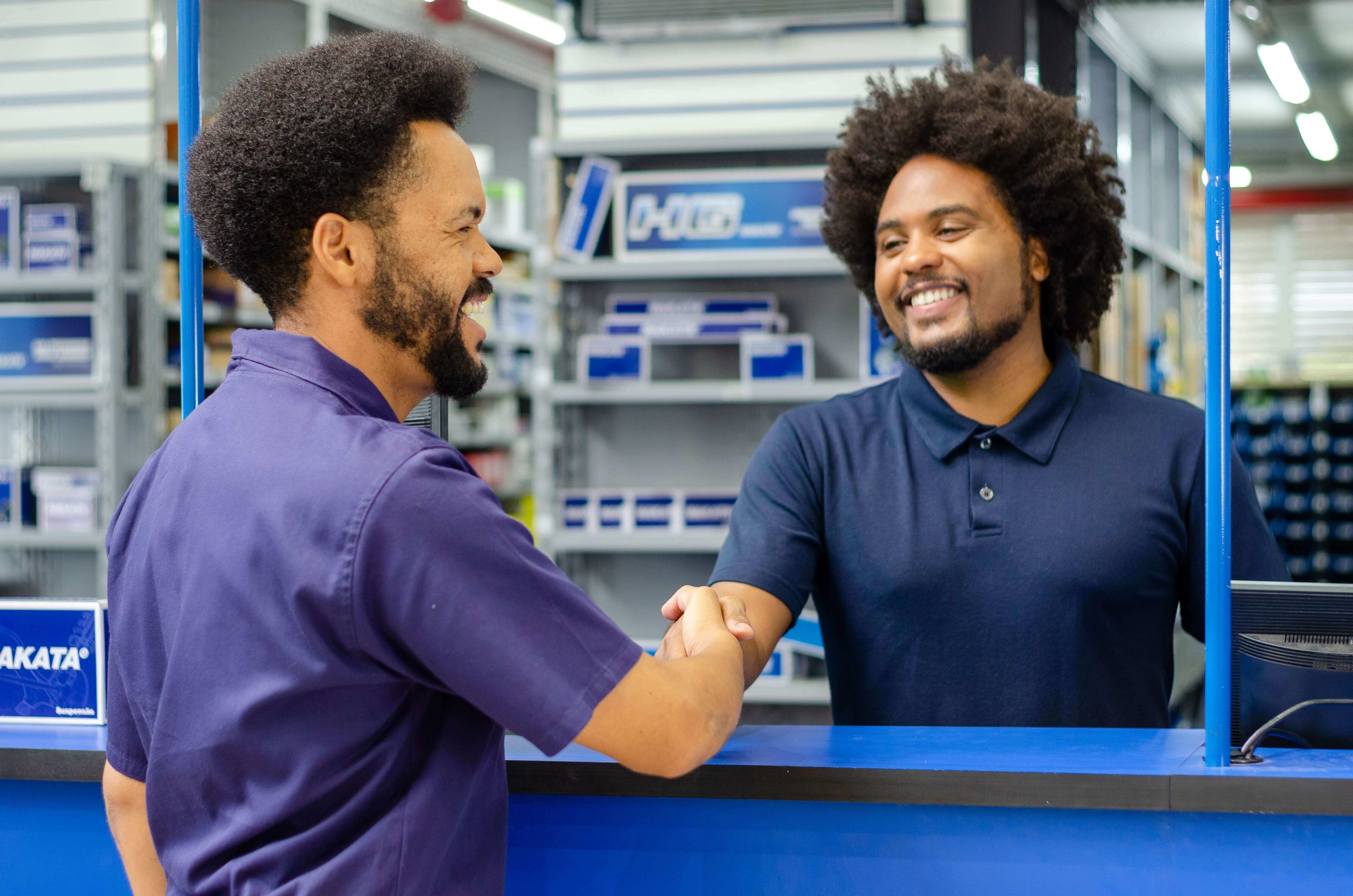 A imagem mostra um vendedor de motopeças fechando venda com mecãnico no balcão