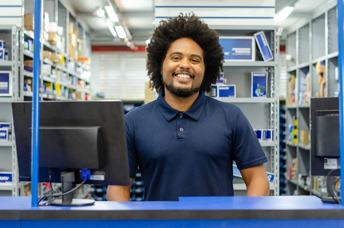 A imagem mostra um vendedor de peças de moto no balcão da loja
