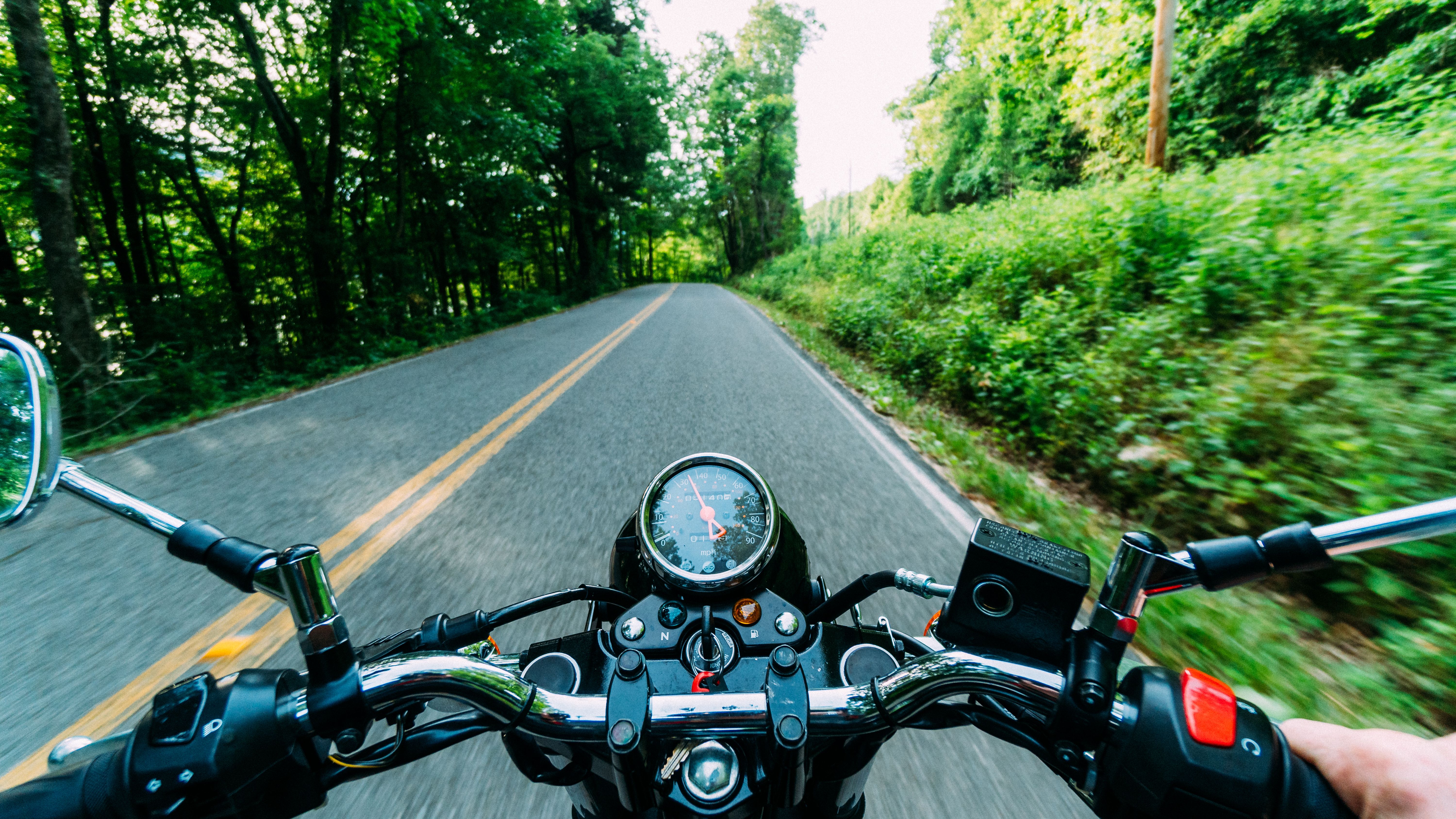 Imagem mostra visão do piloto com o guidão da moto em destaque durante a pilotagem em estrada
